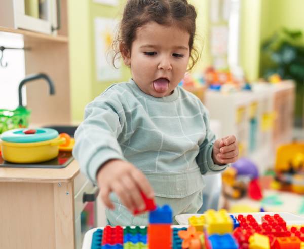 A child plays with colorful building blocks in a vibrant kindergarten classroom.